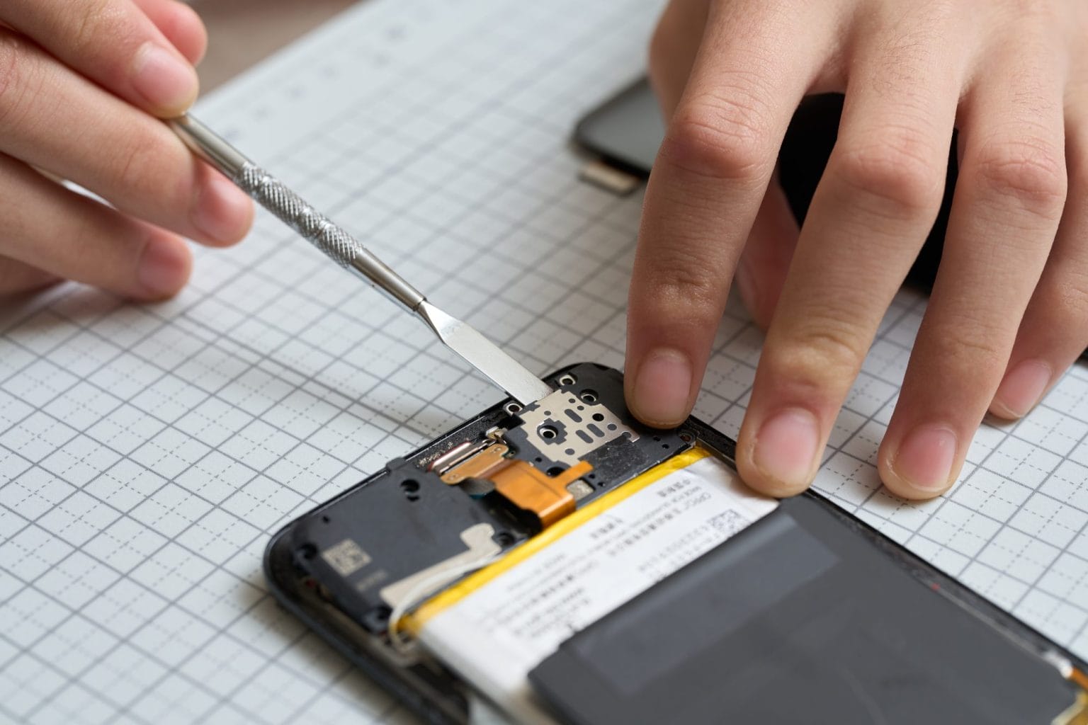 Hands performing disassembly maintenance of smartphones