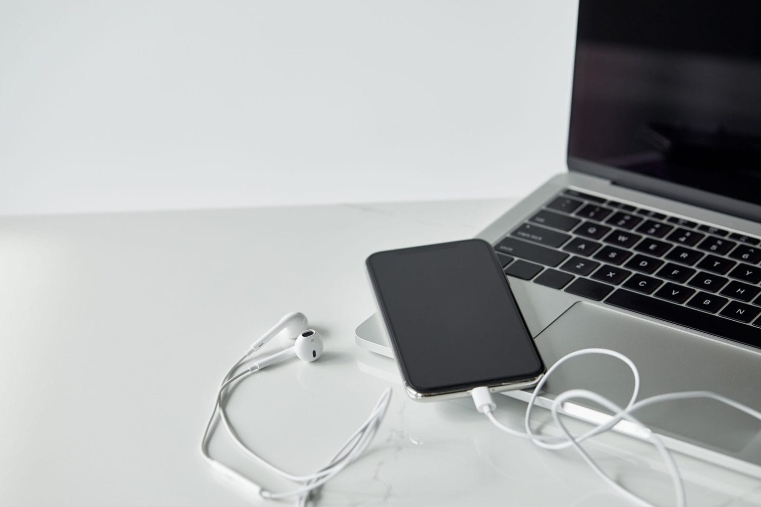 laptop and smartphone with connected earphones isolated on grey