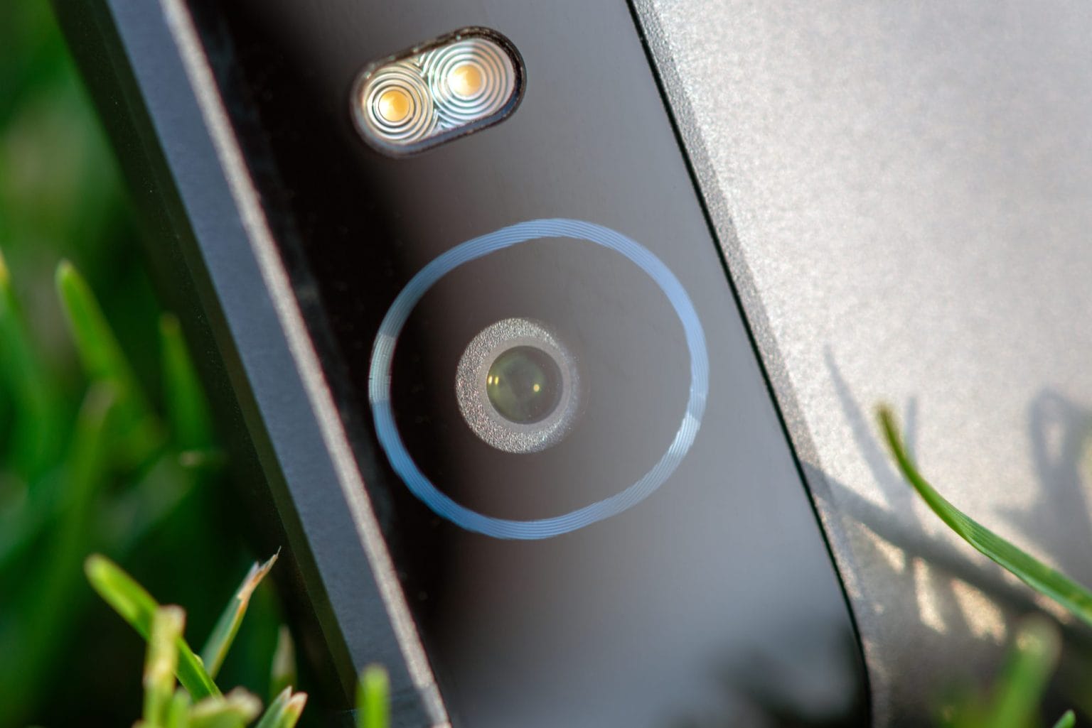 Smartphone camera with a flash close-up photo on green grass
